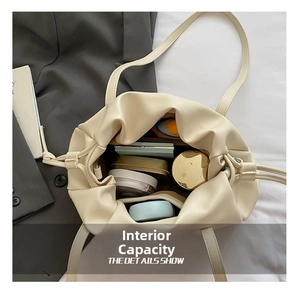Macro shot of spacious inner capacity of cream pleated bucket bag showing cosmetics