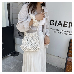 Detail of bohemian hollow-out crochet bucket bag with tassel drawstring and woven strap