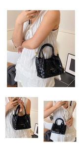 Détail du sac seau noir tressé avec bandoulière dorée et breloques décoratives