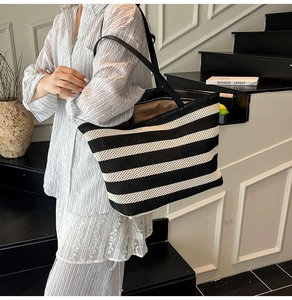 Macro detail of the woven texture and black leather straps on the large striped tote bag