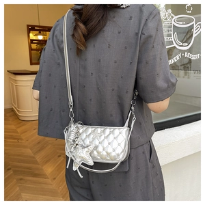 Detail of silver quilted crossbody bag featuring dual metallic star charms and chain strap