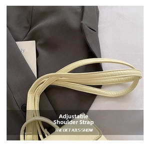 Detail view of the adjustable leather shoulder strap on a cream crossbody handbag