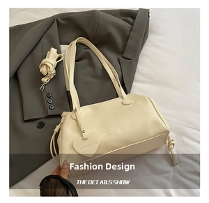 Detail of off-white pleated bucket bag with heart pendant and adjustable strap