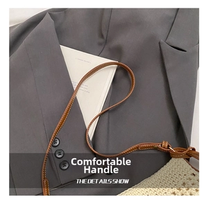 Detail of beige knit tote bag with adjustable brown leather shoulder strap on a grey blazer
