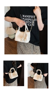 Détail du sac seau tressé blanc avec charm nœud et bandoulière chaîne dorée