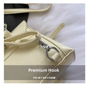 Close-up of polished silver spring hook on a cream-colored leather handbag strap