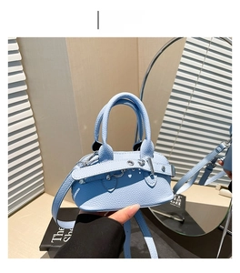 Gros plan du sac à main en cuir bleu clair avec motif litchi et boucles argentées