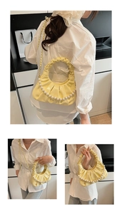 Detail view of a pale yellow pleated hobo bag with pearl strap and gold chain detail