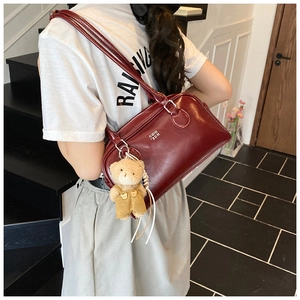 Détail du sac à bandoulière bordeaux brillant avec breloque ours et fermeture éclair