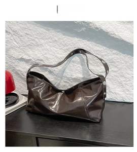 Détail du sac hobo marron café brillant avec de grands clous métalliques argentés sur la bandoulière