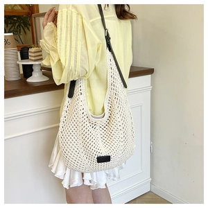 Detail of cream crochet tote bag with contrast black straps in a cafe setting