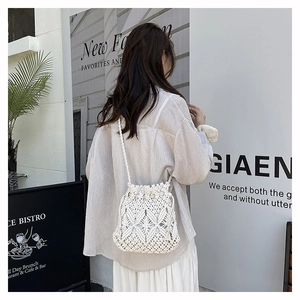 Detailed close-up of white crochet bucket bag with hollow diamond pattern and drawstrings