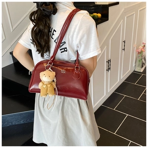 Détail du sac oreiller matelassé bordeaux en cuir verni avec un charmant ours en peluche