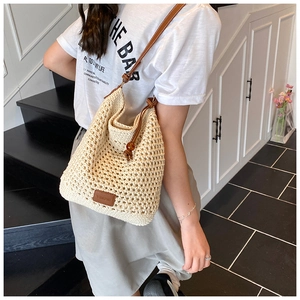 Detail of woven beach tote with leather strap, wooden drawstring and logo patch