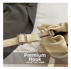 Detail showing high-quality silver metal hook and adjustable strap on beige crossbody bag