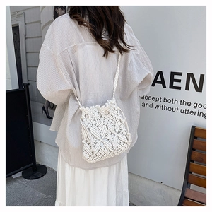 Close-up of white handmade crochet straw crossbody bag with floral hollow texture