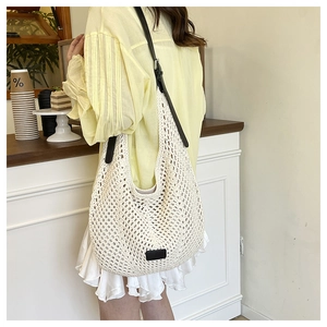 Macro detail of the creamy woven crochet texture and black leather strap on tote bag