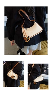 Detail of beige canvas underarm bag with brown leather trim and horse charm