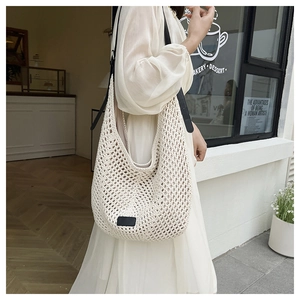 Lifestyle shot of an oversized cream crochet tote bag with a black leather shoulder strap