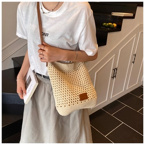Detail of woven crochet tote bag showing openwork mesh texture and brown leather strap
