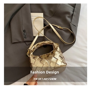 Détail d'un sac seau tissé doré avec poignée épaisse posé sur un blazer gris chic