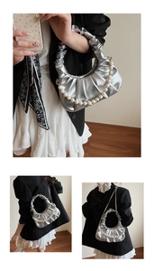 Detail view of silver pleated dumpling bag with pearl handle and metallic finish texture