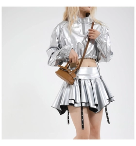 Detailed view of a dark brown mini shell bag with lychee texture held by a model