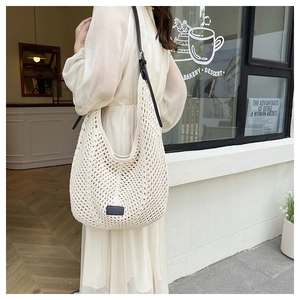 Close-up of beige crochet tote bag with adjustable black leather shoulder strap detail