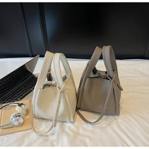 Close-up of pebble leather bucket bags in white and grey with gold hardware