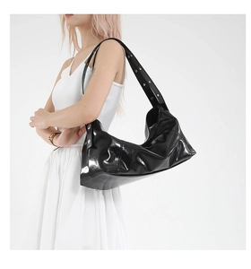 Detail of glossy black hobo bag with wide strap and silver metal eyelet decorations