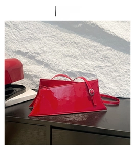 Détail du sac à main asymétrique en cuir verni rouge avec boucle en métal argenté