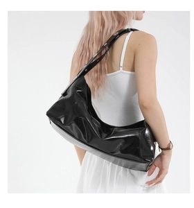 Detail of glossy black patent leather shoulder bag with silver eyelet strap and pleats