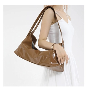 Detail of glossy brown hobo bag with silver metallic eyelets on the shoulder strap