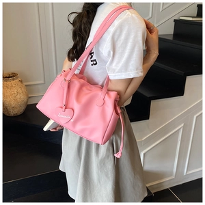 Detail of pink PU leather shoulder bag featuring a side drawstring and heart charm pendant