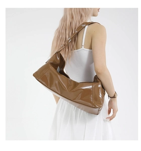 Détail d'un sac bandoulière en cuir ciré marron avec rivets métalliques sur la sangle