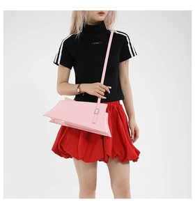 Détail d'un sac bandoulière en cuir verni rose montrant la structure latérale en accordéon
