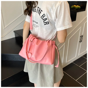 Detailed view of pink leather tote bag with heart charm and brand logo decoration