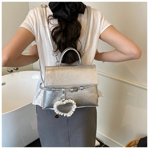 Silver metallic backpack with lace heart charm shown on model in a home setting