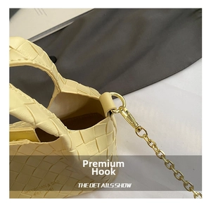 Détail du sac tressé jaune clair avec fermoir en métal doré et logo gravé