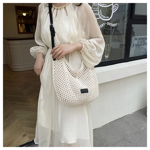 Detail of hollow crochet texture and black adjustable strap on beige hobo shoulder bag