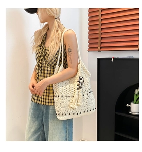 Close-up of bohemian woven tote bag featuring intricate crochet patterns and wood bead tassels