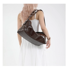 Detail of dark brown hobo bag featuring a wide strap with silver metal rivet studs