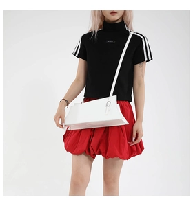 Detailed view of a white leather crossbody bag showing a stylish trapezoid shape and silver buckle