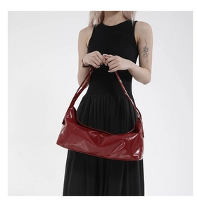 Red glossy faux leather underarm bag shown on a model in a black sleeveless dress