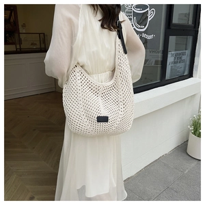 Detail of white crochet tote bag with wide black leather strap and woven mesh texture