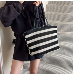 Close-up of black and white striped tote bag with knitted texture and long black handles