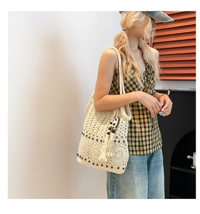 Detail of beige crochet tote bag with wooden beads and boho fringe tassels on side