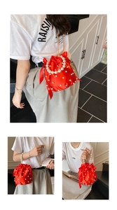 Dettaglio della borsa a secchiello in raso rosso con perle e nastri a fiocco delicati
