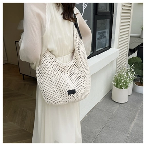 Detail of cream crochet tote bag with mesh hollow design and black shoulder strap