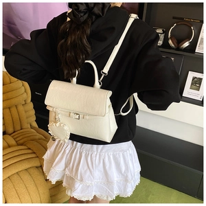 Detail of cream white faux leather backpack with plush heart charm and adjustable straps